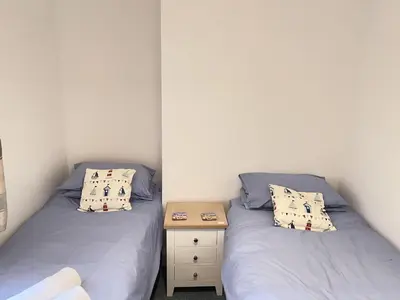 two twin beds in a small room with a table at Lower Seaview in St Ives
