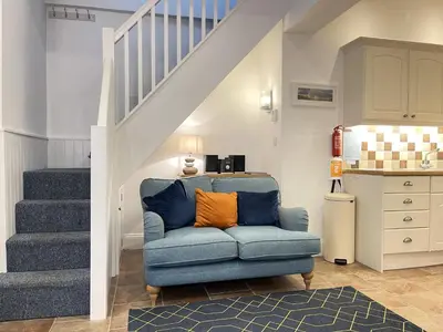 a living room with a blue chair and stairs at Lower Seaview in St Ives