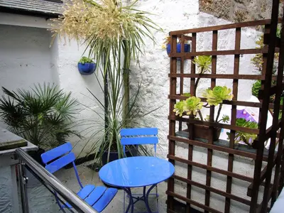 two blue chairs and a table on a balcony with plants at Lower Seaview in St Ives