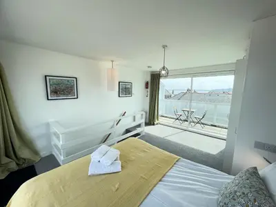 a bedroom with a bed and a large window at 26 Piazza - stunning seaviews of Porthmeor beach in St Ives