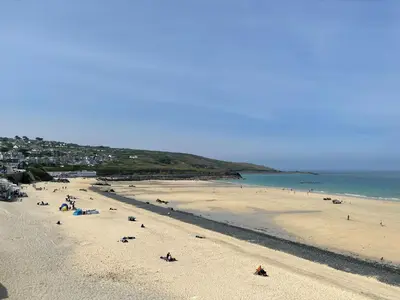 a group of people on a beach near the ocean at 26 Piazza - stunning seaviews of Porthmeor beach in St Ives