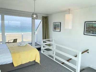 a bedroom with a bed and a view of the beach at 26 Piazza - stunning seaviews of Porthmeor beach in St Ives