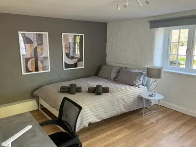 a bedroom with a bed and a table with a chair at Lovely cottage in Penryn centre with parking in Penryn