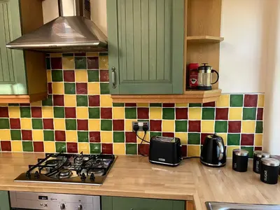 a kitchen with green cabinets and a stove top at Lovely cottage in Penryn centre with parking in Penryn