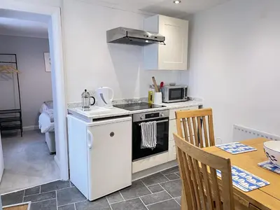 a small kitchen with a stove and a table at Morvah - stunning views of the harbour and beyond in St Ives