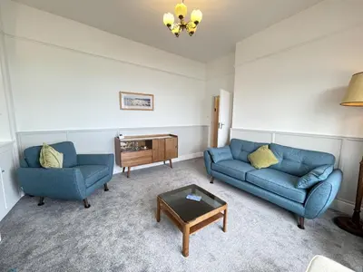 a living room with two blue couches and a coffee table at Morvah - stunning views of the harbour and beyond in St Ives
