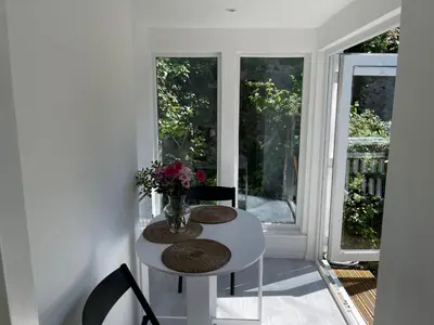 a white table with chairs and a vase of flowers at Dolly - a peaceful retreat in St Ives