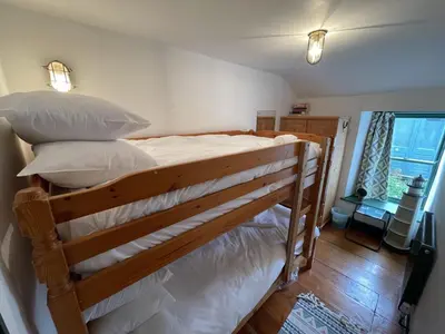 a bunk bed with white sheets and pillows on it at The Green House in St Ives