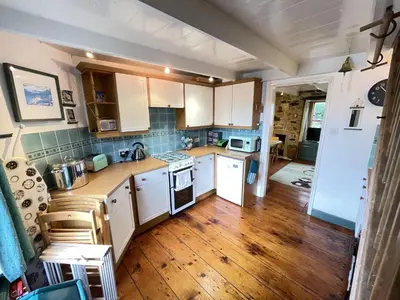 a kitchen with white cabinets and a wooden floor at The Green House in St Ives