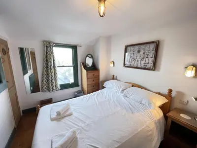 a bedroom with a white bed and a mirror at The Green House in St Ives