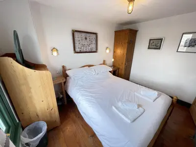 a small bedroom with a bed with white sheets at The Green House in St Ives