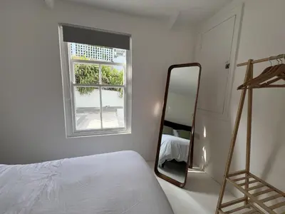 a white bedroom with a mirror and a bed at 9 Mount Pleasant in St Ives
