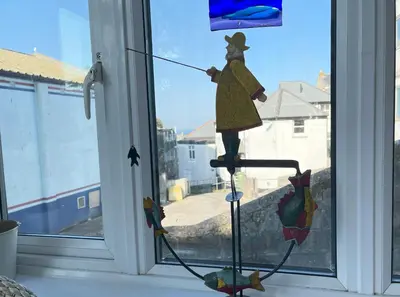 a figurine of a woman on a pole in front of a window at Step n Sea - moments from the town centre and sea in St Ives