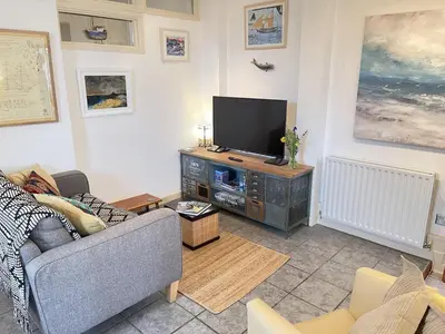 a living room with a couch and a flat screen tv at Step n Sea - moments from the town centre and sea in St Ives