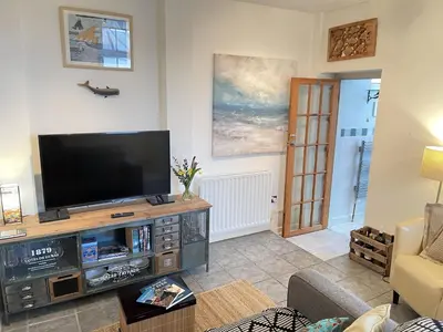 a living room with a flat screen tv on a entertainment center at Step n Sea - moments from the town centre and sea in St Ives
