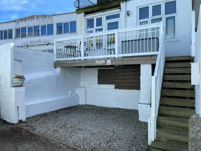 a white house with a balcony and a staircase at Step n Sea - moments from the town centre and sea in St Ives