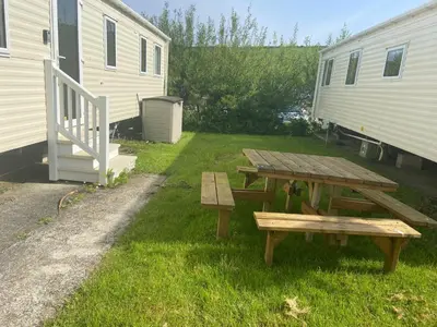 a picnic table in the grass next to a trailer at Newquay Bay - 3-Bed Caravan - Sleeps 6 in Newquay