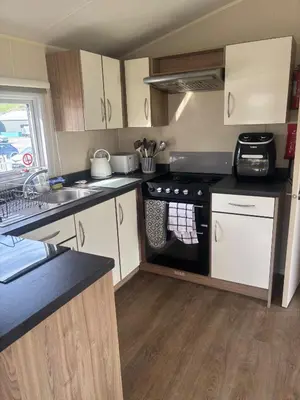 a small kitchen with a stove and a sink at Newquay Bay - 3-Bed Caravan - Sleeps 6 in Newquay