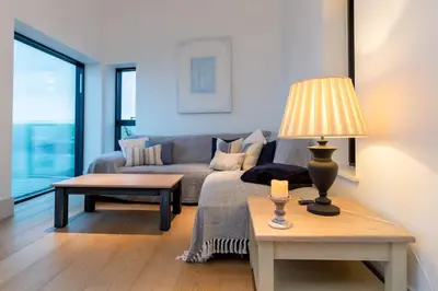 a living room with a couch and a table with a lamp at Holiday home with incredible sea views in Mevagissey