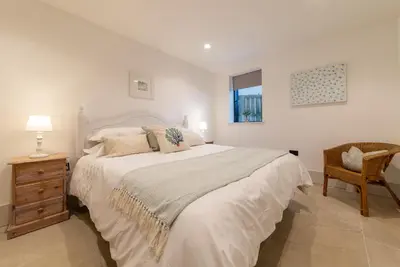a white bedroom with a large bed and a chair at Holiday home with incredible sea views in Mevagissey