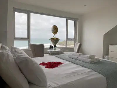 a bedroom with a large white bed with a large window at Ten Ocean View in St Ives