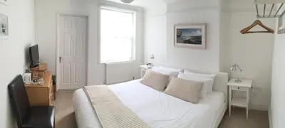 a white bedroom with a bed and a window at Ten Ocean View in St Ives