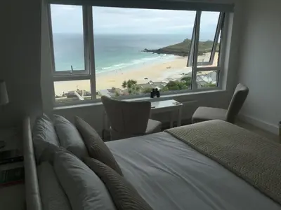 a bedroom with a bed and a view of a beach at Ten Ocean View in St Ives