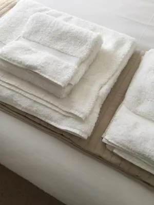 a pile of white towels sitting on top of a bed at Ten Ocean View in St Ives