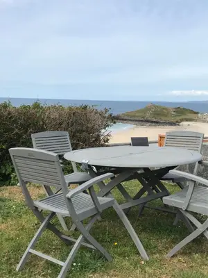 a picnic table and chairs with a beach in the background at Ten Ocean View in St Ives