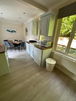 a kitchen with white cabinets and a table with chairs at Luxury, Tranquillity Near Beach in Carbis Bay
