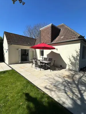 a patio with a table and a red umbrella at Luxury, Tranquillity Near Beach in Carbis Bay