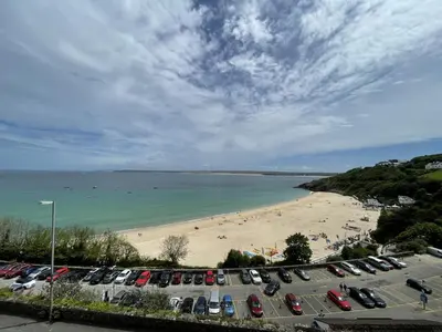 a parking lot next to a beach with cars parked at 36 Carrack Widden in St Ives