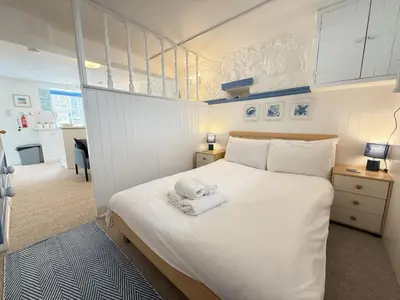 a bedroom with a white bed with a stuffed animal on it at Surfers Nest a modern fisherman lodge in St Ives