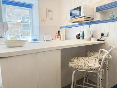 a kitchen with a counter and a chair at Surfers Nest a modern fisherman lodge in St Ives
