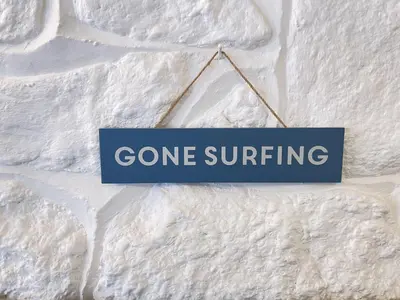 a sign that says gone surfing hanging on a wall at Surfers Nest a modern fisherman lodge in St Ives