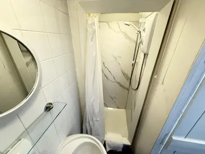 a bathroom with a shower and a toilet and a mirror at Surfers Nest a modern fisherman lodge in St Ives
