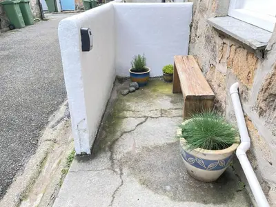 a bench and potted plants on the side of a building at Surfers Nest a modern fisherman lodge in St Ives