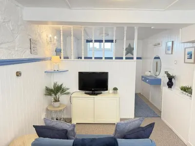 a living room with a tv and blue chairs at Surfers Nest a modern fisherman lodge in St Ives