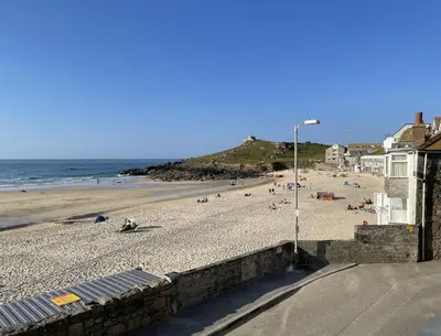 a beach with people on the sand and the ocean at 4 Crusoes - beachside apartment in St Ives