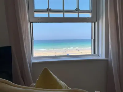 a window with a view of a beach and the ocean at 4 Crusoes - beachside apartment in St Ives