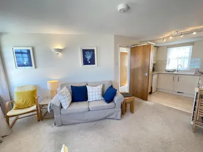 a living room with a couch and a kitchen at 4 Crusoes - beachside apartment in St Ives