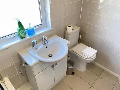 a white bathroom with a toilet and a sink at 4 Crusoes - beachside apartment in St Ives
