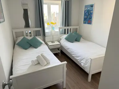 two twin beds in a small room with a window at 4 Sunday School Court in St Ives