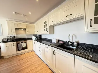 a kitchen with white cabinets and black counter tops at 4 Sunday School Court in St Ives