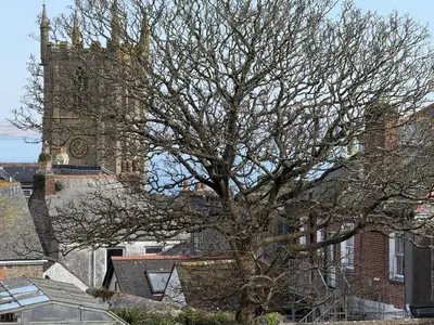 a tree in front of a church with a tower at 4 Sunday School Court in St Ives