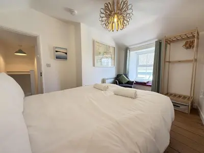 a bedroom with a large white bed and a chandelier at An Argh Vyghan - the little ark in St Ives