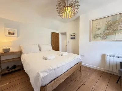 a bedroom with a large bed with a chandelier at An Argh Vyghan - the little ark in St Ives