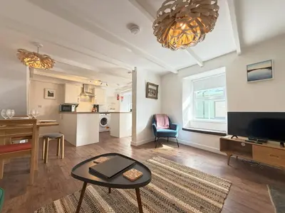 a living room with a table and a television at An Argh Vyghan - the little ark in St Ives