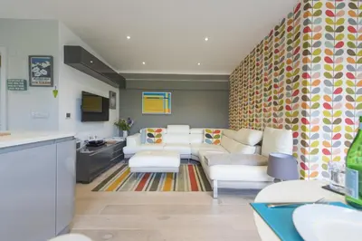 a living room with white chairs and a couch at Two Bare Feet in Truro