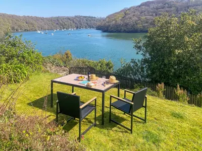 a table with chairs and a view of a lake at Riverside in Truro